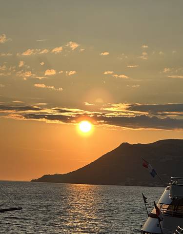 Golden sunset with clouds, a mountain peak in the foreground.