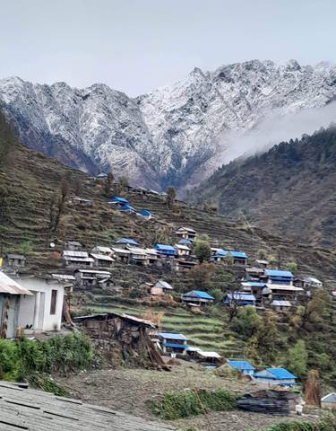 Village in the mountains with blue rooftops and terraced fields.