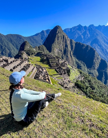 Person sitting overlooking the archaeological site of Machu Picchu.