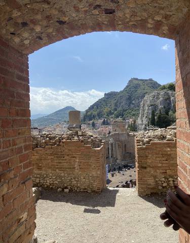 View of an ancient amphitheater with a city backdrop.