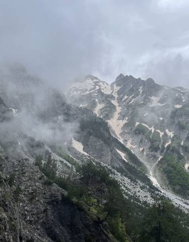Misty mountainous landscape with patches of snow.