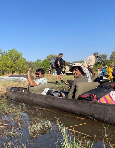 People in small boats on a calm water body in a natural setting.