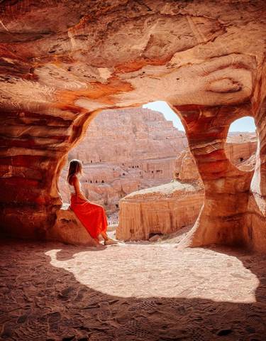 Woman sitting inside a natural rock formation with views of Petra