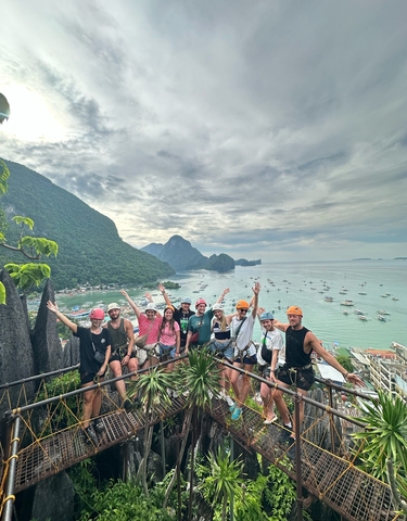 Group of people with helmets posing with a scenic coastal view
