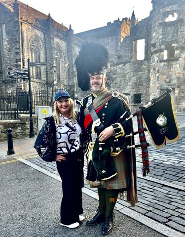 Tourist with a bagpiper in traditional attire.