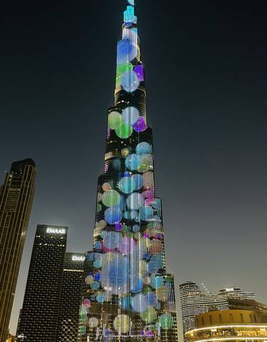 Tall skyscraper with colored lights in the night sky.