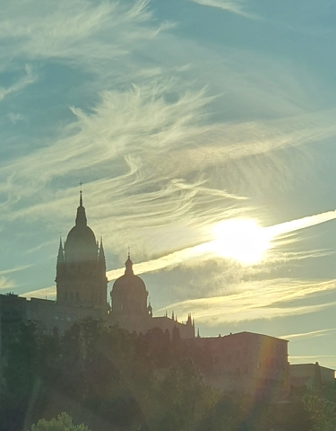 Silhouetted domes and spires of a cathedral at sunset with dramatic clouds.