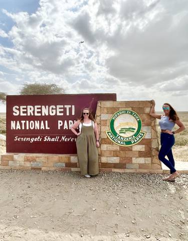 Two women posing with a Serengeti National Park sign.