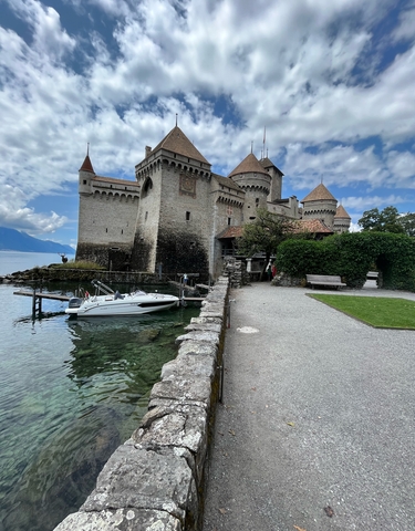 Castle by a lake with a small boat docked nearby.