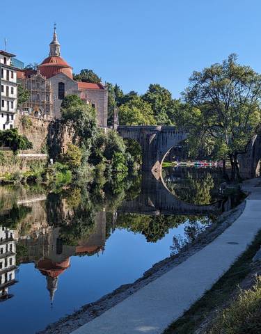 Historic stone bridge over a serene river with clear reflections.