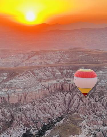 Single hot air balloon floating over a canyon.