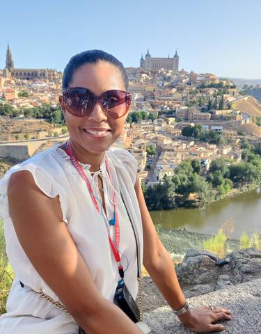 Woman enjoying a scenic overlook with a historical city in the background.