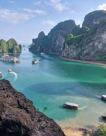 Tourist boats navigating turquoise waters with towering limestone cliffs.