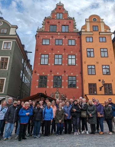 A group of people in front of colorful historic buildings in a European square.
