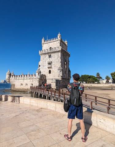 Person in front of the Belem Tower on a sunny day.