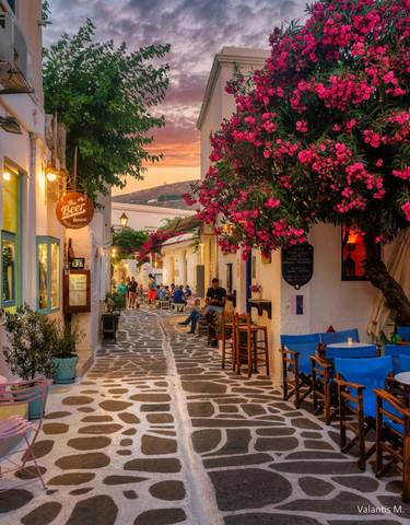 Charming street with colorful flowers and cafes at sunset.