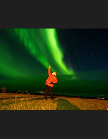 Person pointing at the Northern Lights.