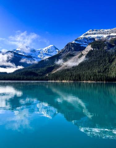 Pristine lake surrounded by dense forest and mountains.