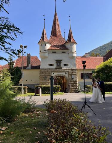 A couple in wedding attire in front of historical architecture.