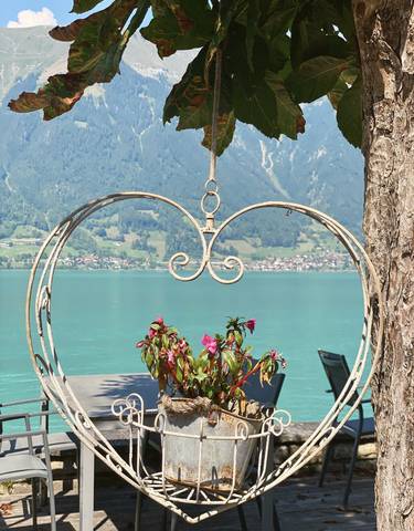Heart-shaped ornament hanging in front of a lake with mountains.