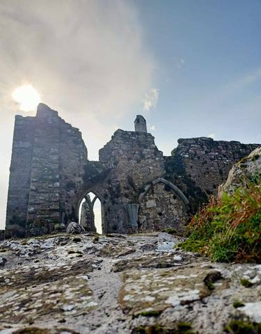Old stone structure with arches against a bright sky.