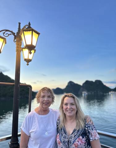 Women smiling with a lovely bay and limestone formations in the background.