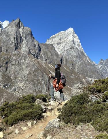 Person looking at a towering mountain in a rocky landscape.