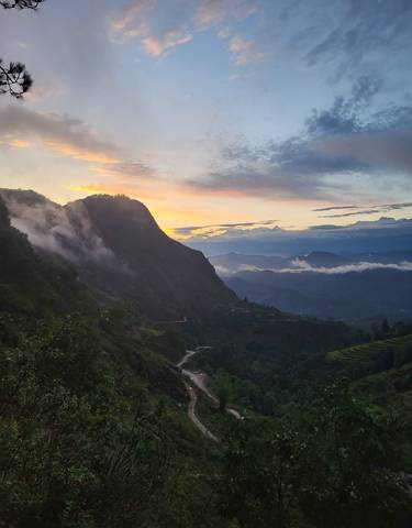 Dramatic mountain landscape with fog and winding road.