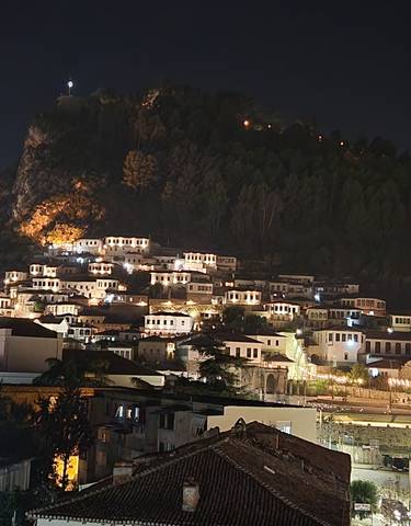 Night view of a town built on a hillside with bright lights.