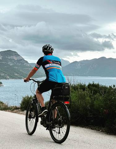 Cyclist overlooking a coastal view with mountains.
