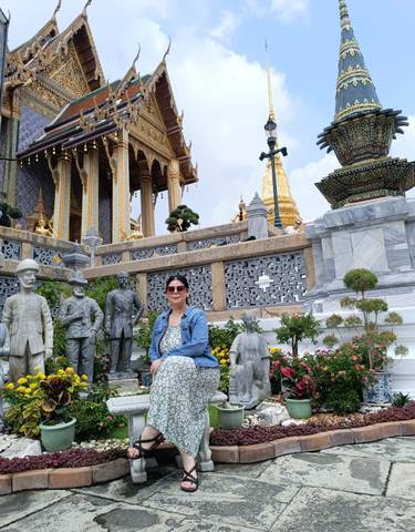 Tourist sitting among statues at a cultural site.
