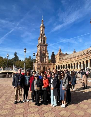 A group of people posing in front of the Plaza de España, a landmark in Seville, Spain.