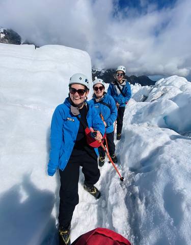 Group of people on a glacier hike wearing helmets and gear.