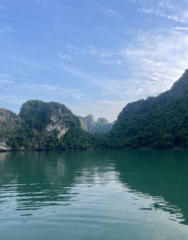 Dramatic limestone hills and green water under a blue sky.
