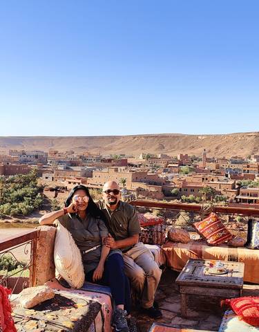 Couple smiling with a townscape and desert hills in the background.