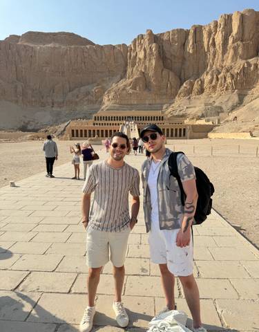 Two people standing in front of an ancient Egyptian temple.