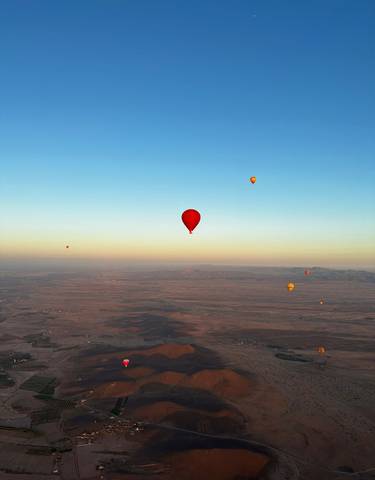 Hot air balloons above a vast landscape during sunrise.