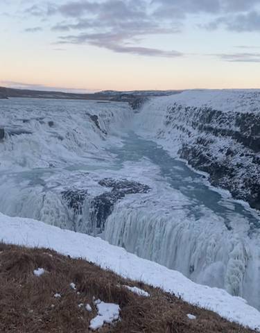 Snow-covered waterfall with icy surroundings.
