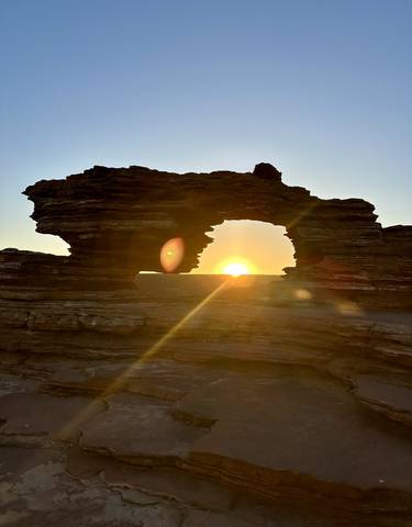 Natural rock formation with sunset through an arch