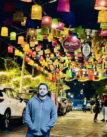 Person seen under vibrant hanging decorations with night lighting.