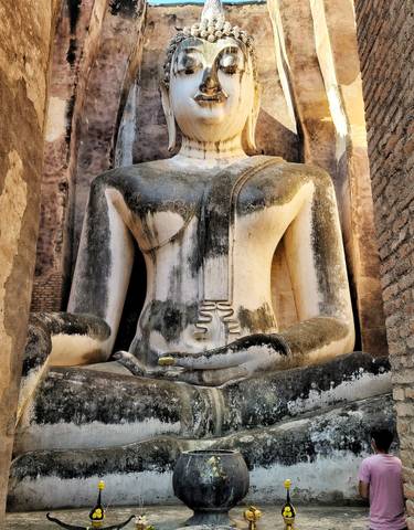 Ancient seated Buddha statue in a historical setting.