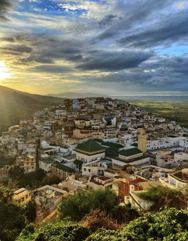 Panoramic view of a city on a hill during sunset.