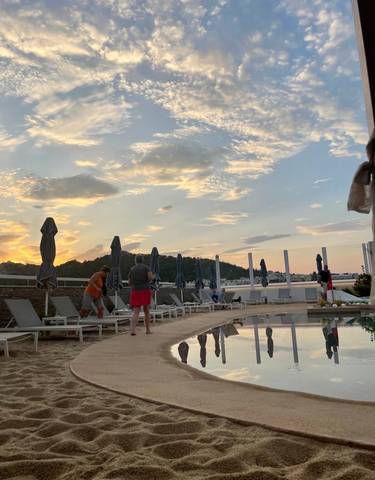 People enjoying poolside relaxation at sunset.