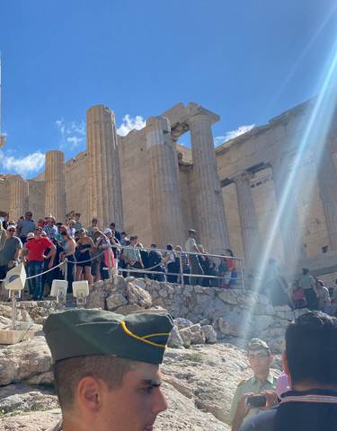 Tourists visiting the Acropolis with columns and blue sky.