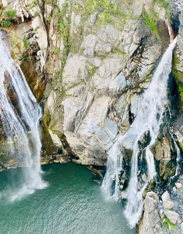 Cascading waterfalls over rocky cliffs into a pool.