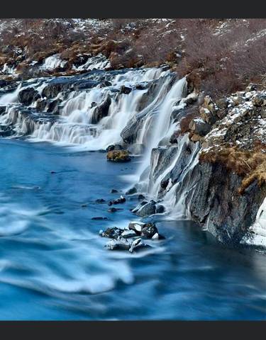 Frozen waterfall in a rocky setting with icy water.