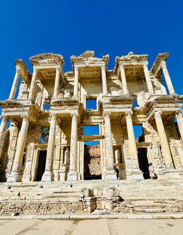 Facade of an ancient library with detailed carvings and bright sky.