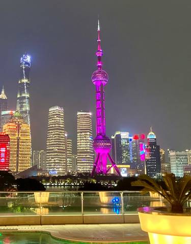 Shanghai skyline lit up at night, with the Oriental Pearl Tower prominently visible.