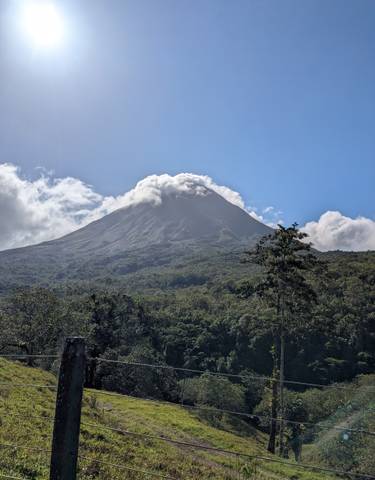 A mountain with a cloud-covered peak under clear blue sky.