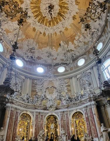 Interior of a richly decorated dome with sculptures and chandeliers.